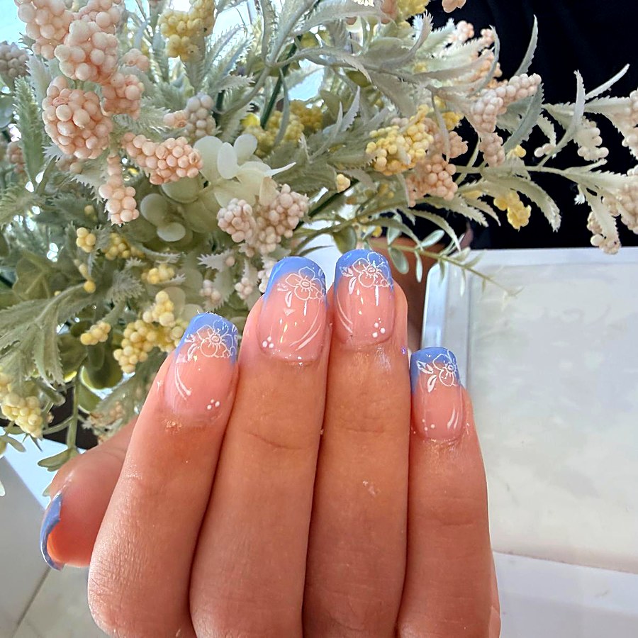 Manicura corta con puntas azules y flores blancas