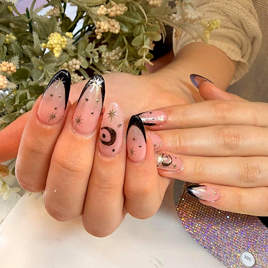 Manicura con puntas negras y detalles de estrellas y luna